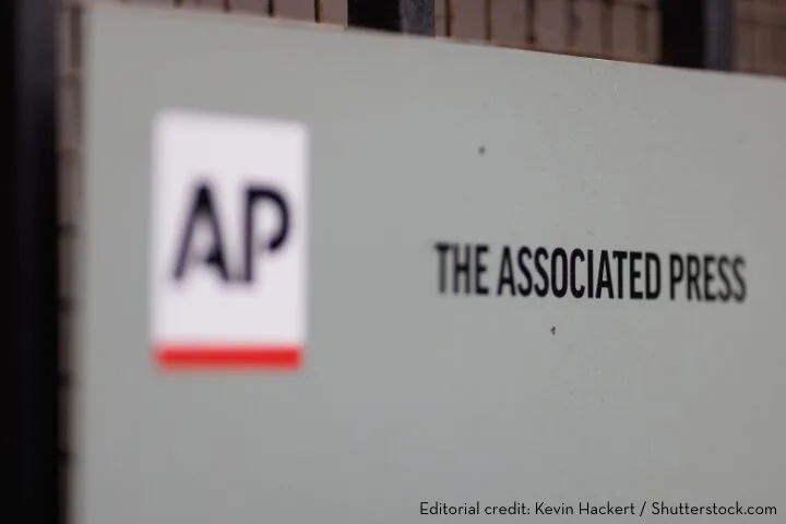 A sign displaying the Associated Press (AP) logo and the words THE ASSOCIATED PRESS on a wall. Editorial credit: Kevin Hackert / Shutterstock.com.